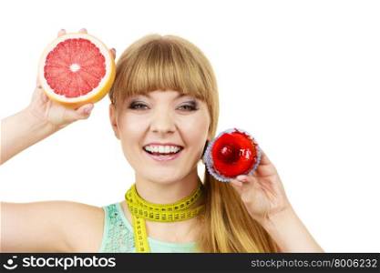 Woman with measuring tape holds in hands cake and grapefruit choosing, deciding between sweet food or fresh fruit, make dietary choice. Weight loss diet dilemma concept. Isolated on white
