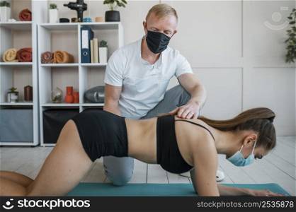 woman with medical mask doing exercises physiotherapy with male physiotherapist