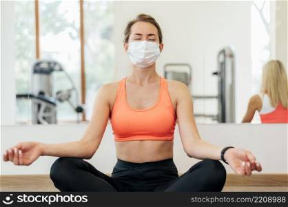 woman with medical mask doing yoga gym