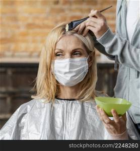 woman with medical mask getting her hair dyed by hairdresser home
