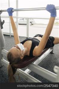 woman with medical mask gloves working out gym