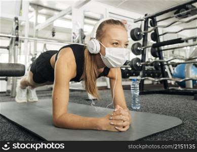 woman with medical mask headphones working out gym