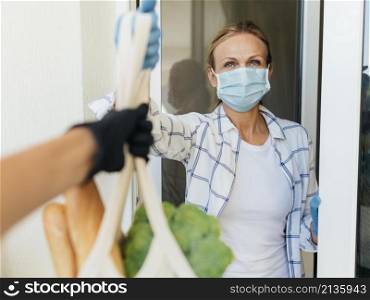 woman with medical mask home picking up her groceries self isolation