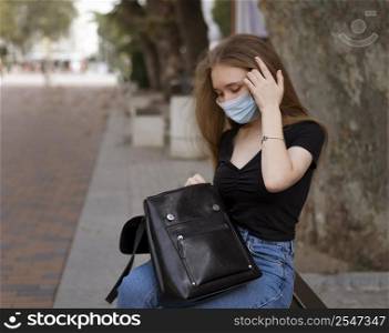 woman with medical mask sitting bench outside