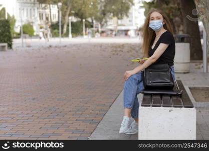 woman with medical mask sitting bench outside with copy space