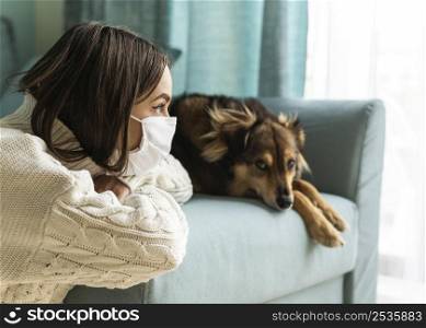 woman with medical mask sitting her dog home during pandemic