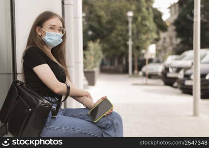 woman with medical mask sitting outdoors