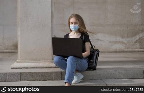 woman with medical mask sitting stairs outside