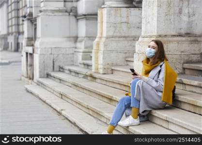 woman with medical mask sitting steps using smartphone