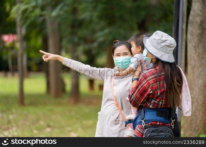 woman with medical mask to protect coronavirus covid-19  while holding baby in the zoo