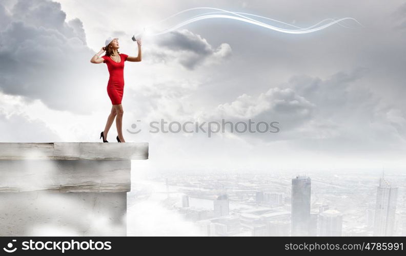 Woman with megaphone. Pretty woman in red dress screaming in megaphone