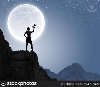 Woman with megaphone. Silhouette of woman on top of rock screaming in megaphone