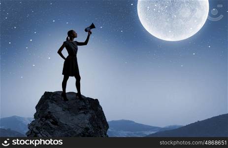 Woman with megaphone. Silhouette of woman on top of rock screaming in megaphone