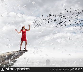 Woman with megaphone. Young woman in red dress speaking in megaphone