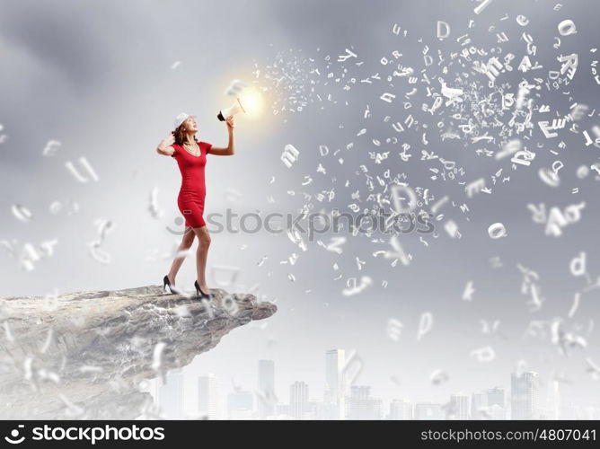 Woman with megaphone. Young woman in red dress speaking in megaphone