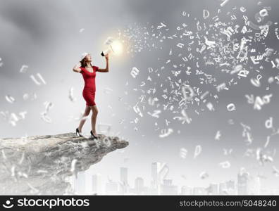 Woman with megaphone. Young woman in red dress speaking in megaphone