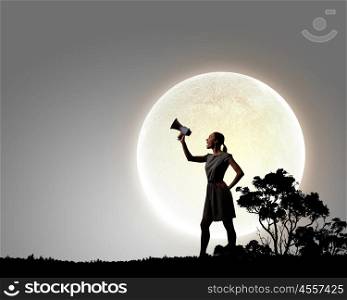 Woman with megaphone. Young woman speaking in megaphone against full moon