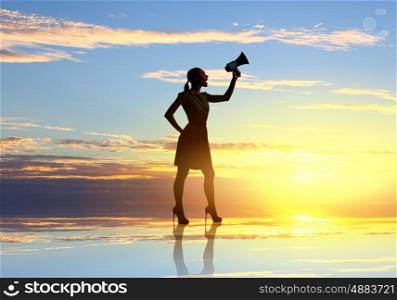 Woman with megaphone. Young woman speaking in megaphone against sunrise