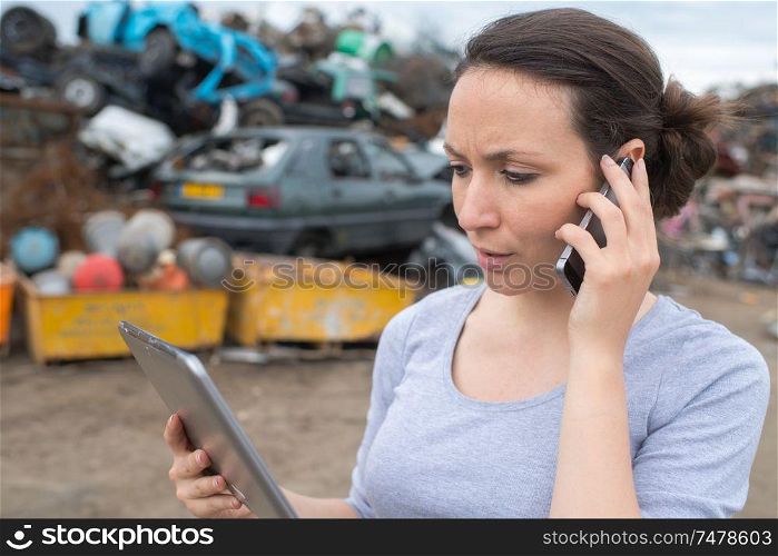 woman with mobile phone and file folder outside factory