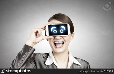 Woman with mobile phone. Beautiful young woman holding mobile phone against her eyes