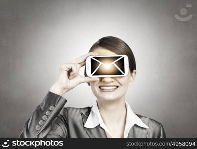 Woman with mobile phone. Beautiful young woman holding mobile phone against her eyes