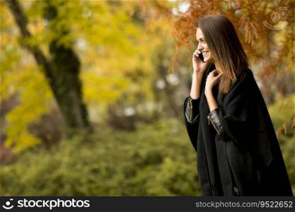 Woman with mobile phone in the autumn park