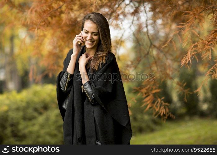 Woman with mobile phone in the autumn park