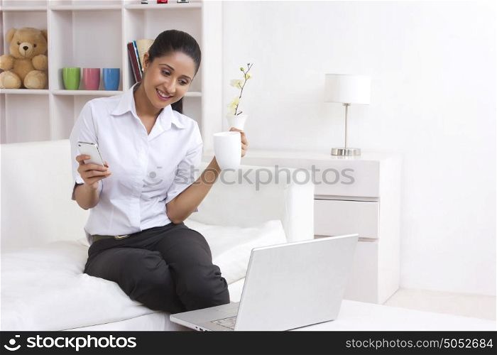 Woman with mobile phone looking at laptop
