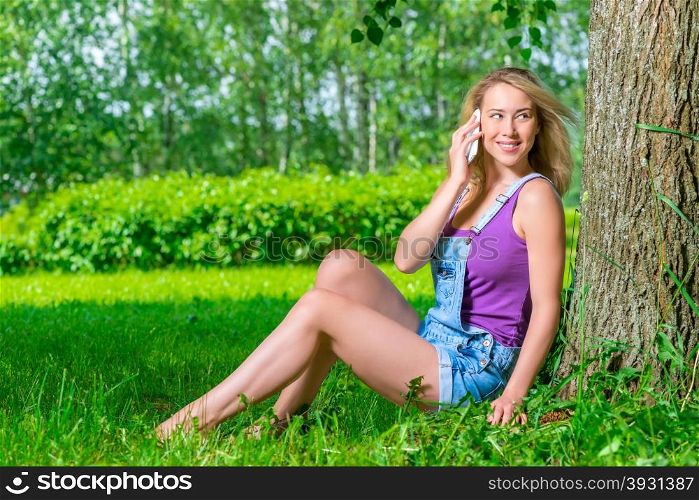 woman with mobile phone sitting on the grass in the park
