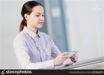 Woman with mobile phone. Woman standing at balcony and sending text from her mobile phone