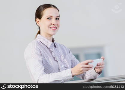 Woman with mobile phone. Woman standing at balcony and sending text from her mobile phone