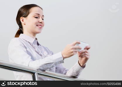 Woman with mobile phone. Woman standing at balcony and sending text from her mobile phone