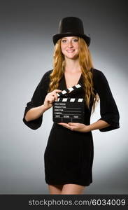 Woman with movie clapboard against grey background