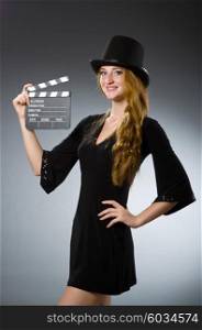 Woman with movie clapboard against grey background
