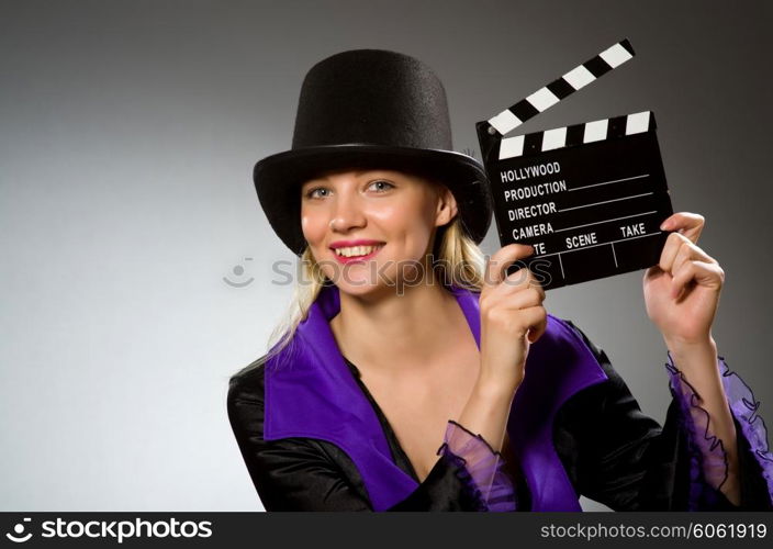 Woman with movie clapboard against grey background