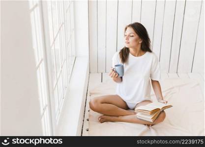 woman with mug book enjoying sunlight