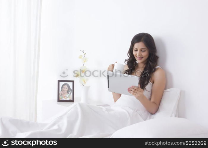 Woman with mug of tea and digital tablet