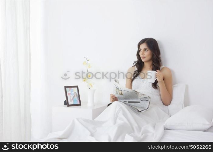 Woman with mug of tea and newspaper