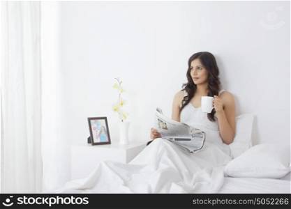 Woman with mug of tea and newspaper