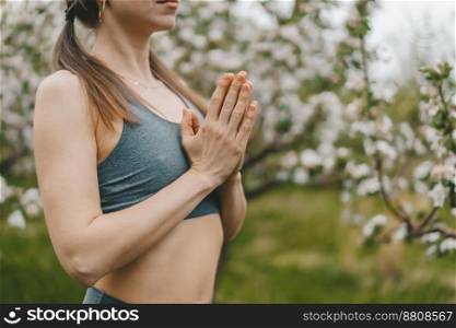 Woman with namaste yoga mudra hands on spring blossom garden natural background. Healthy girl training at outdoors. Gratitude, unity with nature, peace and love concept. High quality photo. Woman with namaste yoga mudra hands on spring blossom garden natural background. Healthy girl training at outdoors. Gratitude, unity with nature, peace and love concept.