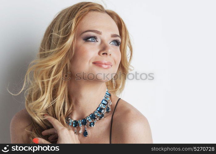 Woman with necklace. Portrait of beautiful woman with blonde curly hair and necklace of blue precious stones close up