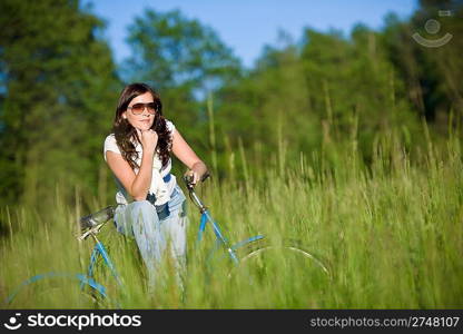 Woman with old-fashioned bike in summer meadow on sunny day