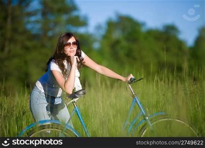 Woman with old-fashioned bike in summer meadow on sunny day