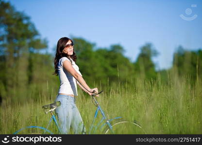 Woman with old-fashioned bike in summer meadow on sunny day