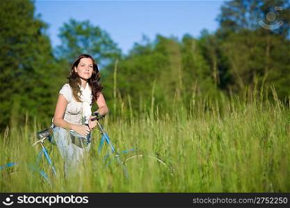Woman with old-fashioned bike in summer meadow on sunny day