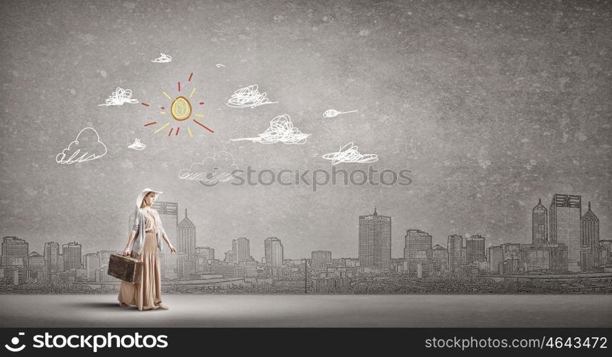 Woman with old suitcase. Beautiful woman walking with retro suitcase on cityscape background