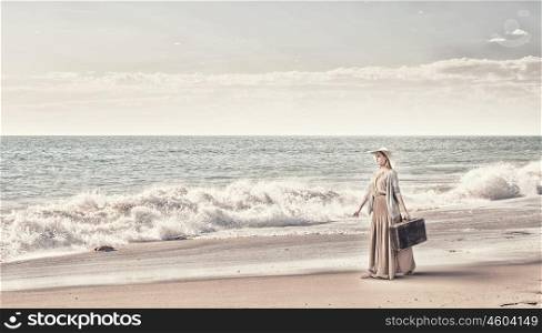 Woman with old suitcase. Beautiful woman with retro suitcase walking alongside sea coast