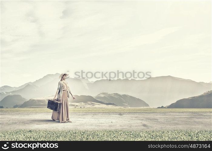 Woman with old suitcase. Beautiful woman with retro suitcase walking in green meadow