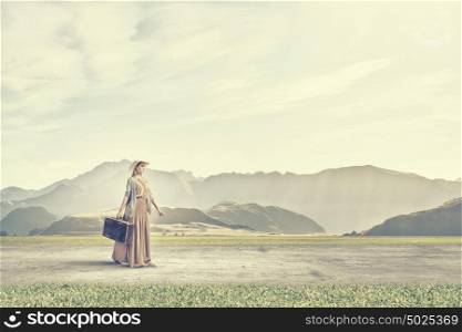 Woman with old suitcase. Beautiful woman with retro suitcase walking in green meadow