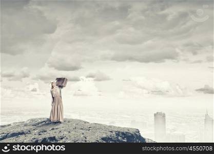 Woman with old suitcase. Beautiful woman with retro suitcase walking on hill top